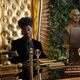 Lil Nas X sits at a golden desk at Riot Games' office.